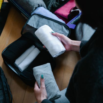 Person packing folded clothes in a suitcase